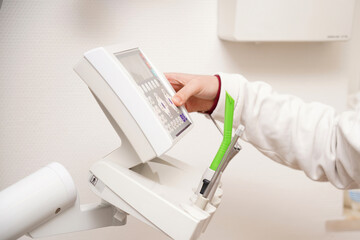 The dentist prepares for work and sets up the remote control for examining teeth.