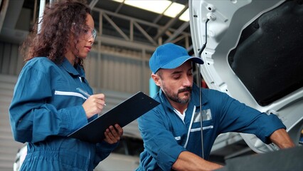 Two Auto mechanic checking car engine oil in car auto repair service center. Car repair and...