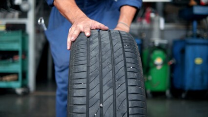 Fototapeta na wymiar Hand of mechanic push car tires at garage in the auto repair service center