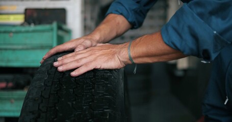 Hand of mechanic push car tires at garage in the auto repair service center