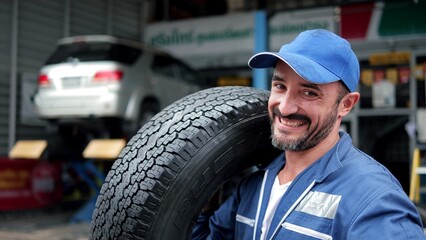 Male mechanic with car tire in auto store, Specialist tire fitting in the car service, checks the...