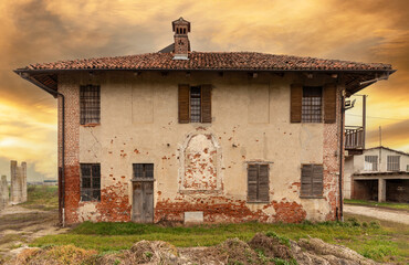 Old abandoned farmhouse with typical rural architecture of the Po Valley in the province of Cuneo, Italy