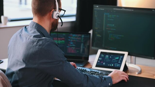 Programmer is working in the modern office. Sitting by computer.