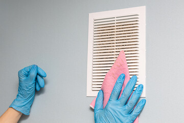 Man cleaning the ventilation grill in the room.