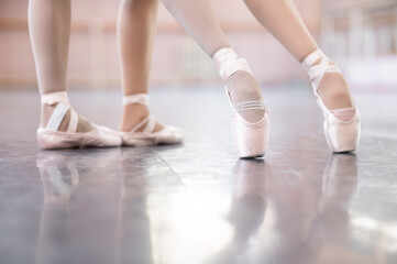 Close-up of the legs of two ballerinas in pointe shoes in a dance class.