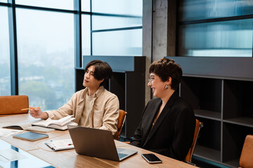 Two smiling coworkers working together during meeting in office