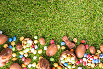 Easter egg hunting background. Various candy and chocolate Easter eggs, bunny and rabbits with...