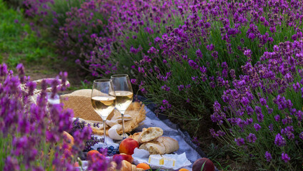 wine, fruits, berries, cheese, glasses picnic in lavender field. Selective focus