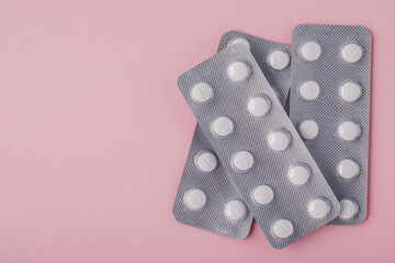 Pills in blister pack on pink background, top view