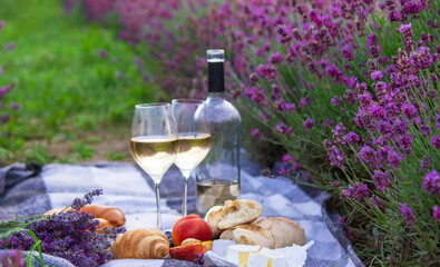 wine, fruits, berries, cheese, glasses picnic in lavender field. Selective focus