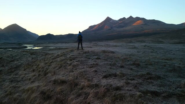 Slow pan to Black Cuillin at dawn with hiker on Isle of Skye Scotland