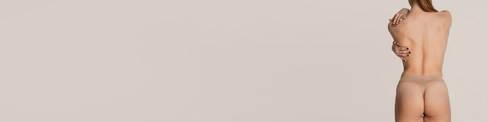 Naklejka premium Rear view of slender woman with perfect body shape in underwear posing over grey background. Concept of health, beauty, body and skin care, anti-cellulite program