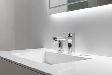 Close-up of white sink with large and small taps for filtering drinking running water. Concept of clean drinking water and high-tech purification system