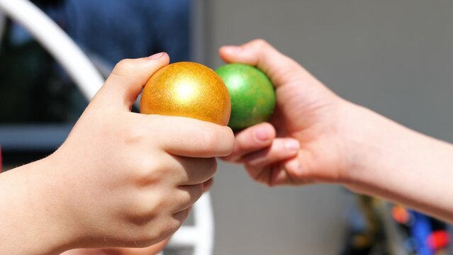 Two kind beat colorful green and orange Easter eggs outdoor. Seasonal tradition games in happy Easter holiday. Close up. Knocking eggs figh game.