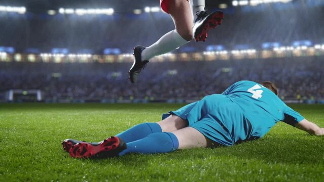 Aesthetic Shot of Red Team Soccer Football Player Successfully Avoiding Sliding Tackle From Opponent on Stadium With Fans Cheering. Super Slow Motion Captures Dangerous Moment During Championship.