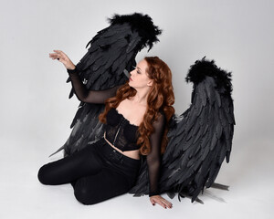 Full length portrait of beautiful woman with long red hair wearing sheer corset top, leather pants...