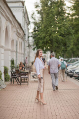 a happy beautiful girl walks around the city in the summer, a girl in a non-Russian image at sunset, a vertical frame, freedom
