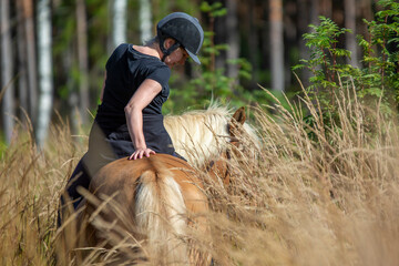 Naklejka na ściany i meble Woman horseback riding in forest trail