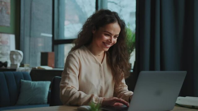 Footage of good-looking young smiling woman stylish dressed working on freelance platform. Portrait of beautiful girl enjoying online work from home. Remote job concept