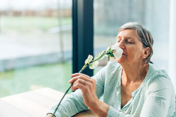 senior woman taking a moment of pleasure smelling the perfume of a flower