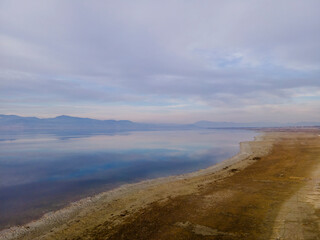 Quiet calm estuary. Peaceful nature. White thick clouds over the pond. Mountains stretch in the background.