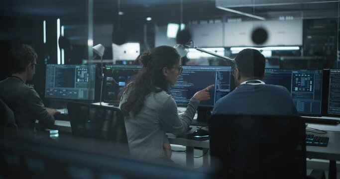Young Team of Specialists Working on Desktop Computers and Having a Conversation at a Workplace. Female and Male Software Developers Discussing a Solution for Their Artificial Intelligence Project
