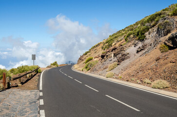 Sharp right bend of winding mountain road and white clouds ahead. Teide National Park, Tenerife,...