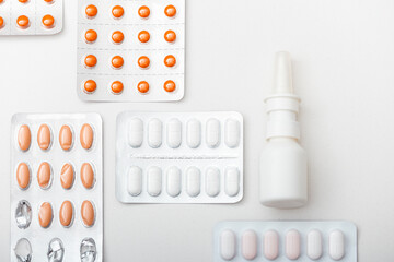 Close-up view from above of nasal spray, pills, white background. Cold, virus, antibiotics,...