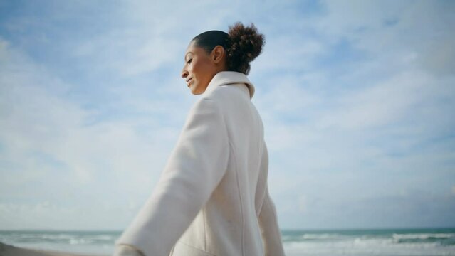 Cheerful woman spinning seashore at cloudy sky. Happy serene girl enjoying rest