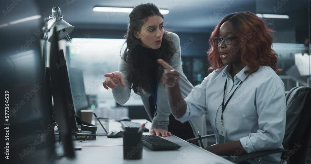 Fototapete two diverse colleagues having a conversation while busy working on a team project. african female de