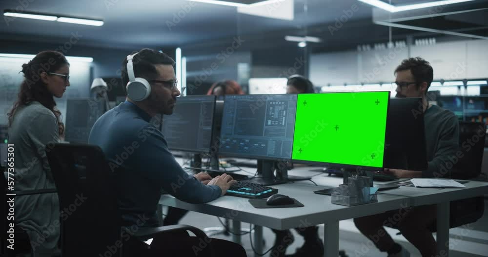 Poster Group of Diverse Multicultural Men and Women Working on Desktop Computers in a Research Center. Young Software Developer Working on a Computer with Two Green Screen Mock Up Displays