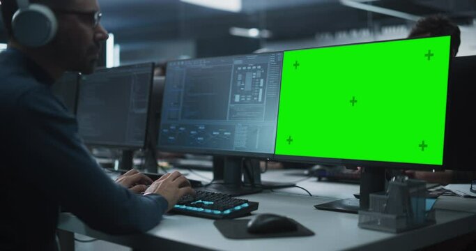 Close Up of a Software Developer Working on a Desktop Computer with Green Screen Mock Up Display. Specialist Typing on Keyboard, Coding and Implementing a New Technical Feature, Working in an Agency