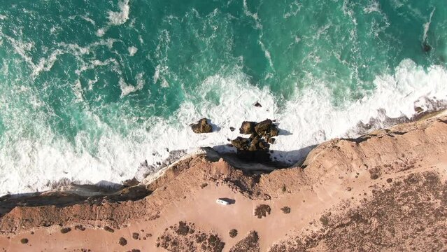 Aerial top down shot of camper van on edge of steep cliffs during sunny day - Nullarbor SA, Australia