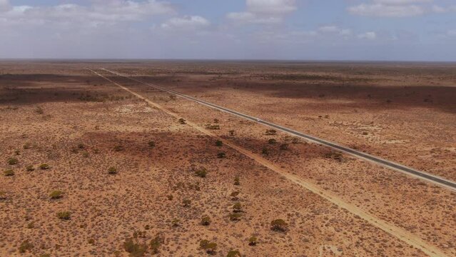 Drone zoom out of campervan on empty road surrounded by dry landscape of Australia - Nullarbor