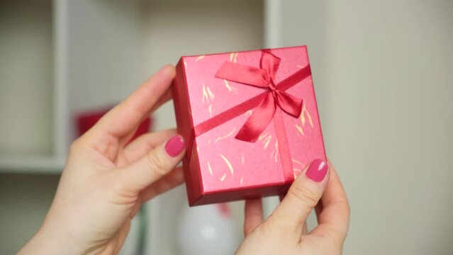 Red box with a gift in women's hands. Concept of gifts, holidays, valentine's day, mother's day, wedding anniversary, birthday
