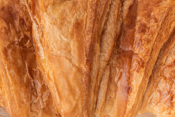 Flat lay of soft croissant with golden crust as a textured background, top close-up view. Macro...