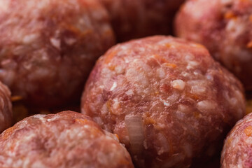 Homemade meatballs with tomato sauce, carrot and spices. Raw ground beef meatballs with rice in a white dish for baking. White marble background. Original way to cook meat