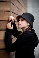 portrait of a cute girl in a black hat on the background of a wooden wall