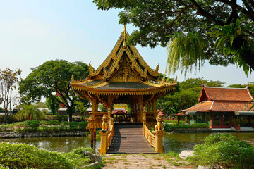 Obraz premium Chinese architecture of pavilion with corridor bridge in the pond with tree and blue sky background in park at Ancient City,Siam,Samutprakan province, Thailand. 