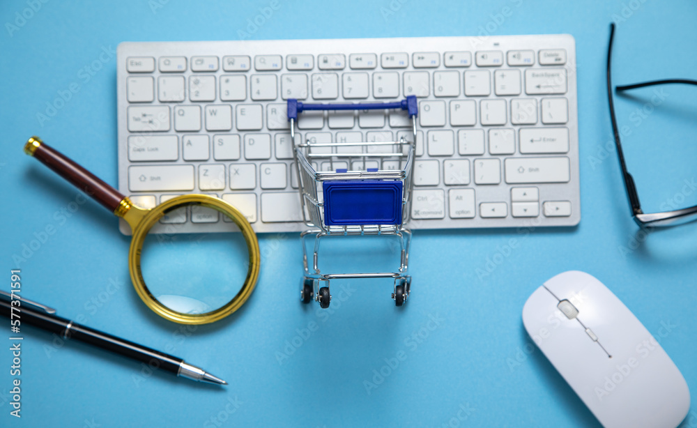 Wall mural Shopping cart with a computer keyboard and business objects.