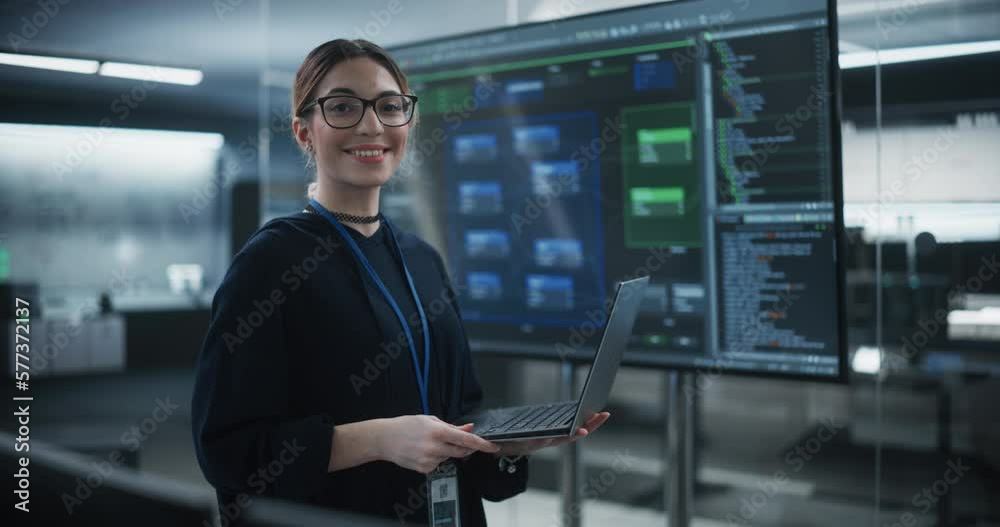Poster portrait of a beautiful diverse female wearing glasses, using laptop computer, looking at camera and