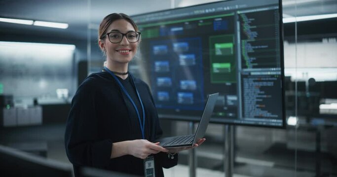 Portrait of a Beautiful Diverse Female Wearing Glasses, Using Laptop Computer, Looking at Camera and Smiling. Information Technology Specialist, Software Engineer or Developer