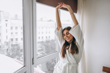 Fototapeta na wymiar Young woman in the morning stretching by the window