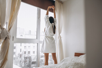 Fototapeta na wymiar Young woman in the morning stretching by the window