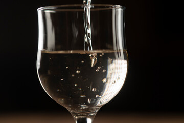 girl hands pouring red wine into a glass from a clay bottle on a black background