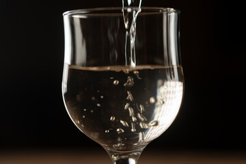 girl hands pouring red wine into a glass from a clay bottle on a black background