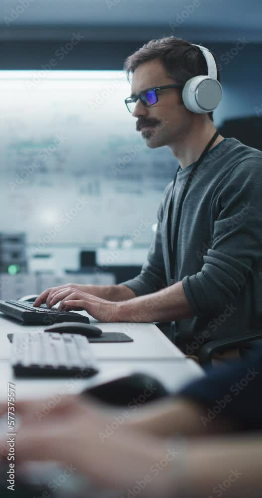 Aufkleber Vertical Screen: System Administrator Working in a Research E-Business Facility on a Computer. Focused Software Developer in Casual Clothes Wearing Headphones and Updating Server System Database