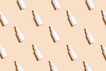 Pattern of anti aging serum in white bottle with dropper on pastel beigh background. Creative...