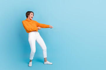 Fototapeta na wymiar Full body photo of attractive young woman pulling rope heavy try hard impressed wear trendy orange outfit isolated on blue color background