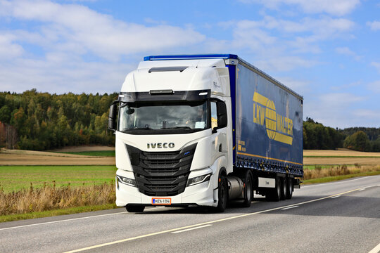 New, white gas-powered Iveco S-Way Natural Power, NP, truck in front of semi trailer on highway on a sunny day. 